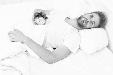 Sabah uyanışı. Uykulu adam çalar saati kapatıyor. Erken kalkmak. Uyanma ve kalkma vakti geldi. Sabah uyanması. Yatakta yatarken elinde çalar saatle uyuyan adam. Uyku bozukluğu.