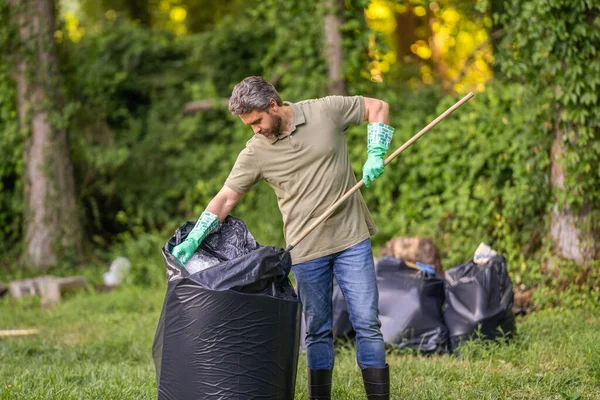 Environmental activist. Environmental conservation and waste pollution. Environment plastic pollution. Volunteer collecting trash in forest into garbage bag. Environmental protection. Green volunteer.