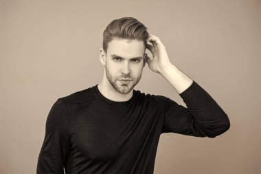 Adamın şık bir saç kesimi var. Moda saç stili olan bir adam. Sıradan erkek tarzı. Beyazlı genç bir adam gri yolda izole edilmiş. Kendine güvenen adam portresi. Erkeklerin cilt bakımı. Erkek derisi. Kuaför..