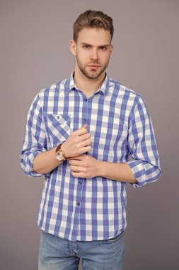 Milenyum erkeğinin gündelik tarzı. Sıradan tişörtlü bir adamın portresi. Tıraşsız adamın zarif portresi. Gri yolda izole edilmiş bir adam. Kareli gömlek giyen milenyum adamı. Minimalist stil.