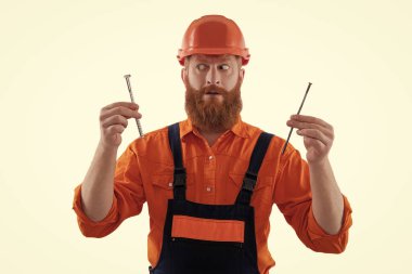 Marangoz, beyaz çiviyle tamir ediyor. Tamirci. Adam çekiç çivisi tutuyor. Marangozluk tamir ve çekiç. Üniformalı tamircinin çivisi var. Sakallı marangoz çivi tutar. Genel DIY araç seti.