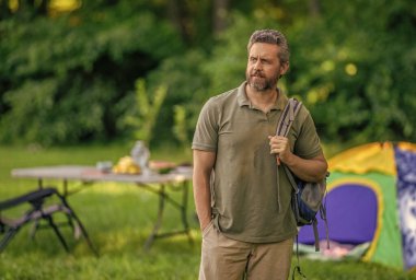 Yaz kampı. Kamp macerası. Yürüyüş yaşam tarzı. Kamp alanındaki adam. Piknik zamanı reklamı. Ormanda çadırlı piknik yapan bir adam. Yaz günü yürüyüş yapan bir adam. Yaz kampı aktivitesi.