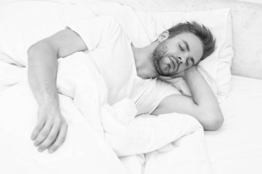 Genç adam uyuyor ya da beyaz yatak odasında evinde uyuyor..