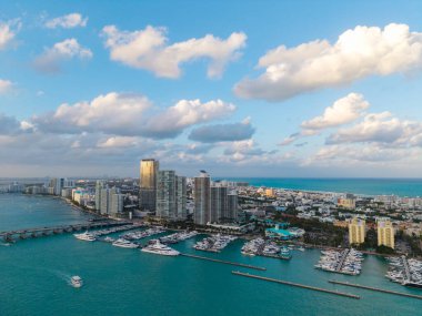 Miami marinasındaki lüks yatların hava manzarası. Miami marinasındaki tekne ve gökdelenlerin manzarası. Miami kıyı şeridi boyunca yelken açan yat.