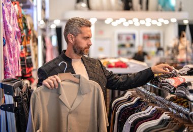 Kıyafet alırken ceketini seçen modaya uygun bir müşteri. Klasik bir kıyafet. Mağaza müdürü şık bir takım elbise gösterdi. Butikte alışveriş yaparken klasik terzilik kıyafeti giyen adam..