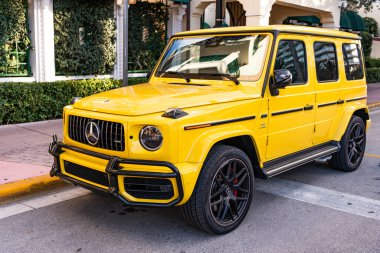 Miami, Florida, ABD - 26 Ocak 2025: Mercedes Benz hibrit araba açık havada park edildi. Sarı araba, köşe manzaralı. 2025 Mercedes Benz G sınıfı hibrit araba. Lüks elektrikli ve motorlu Mercedes Benz G sınıfı..