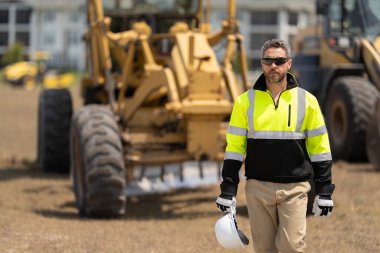 Denetmen işçi üniforma giyer. İşteki en üst düzey yönetici. İşçi bayramı. Binanın dış tarafında. Şantiyedeki adam. İnşaat mühendisliği. İnşaat alanında mühendis var. Genel işçi.