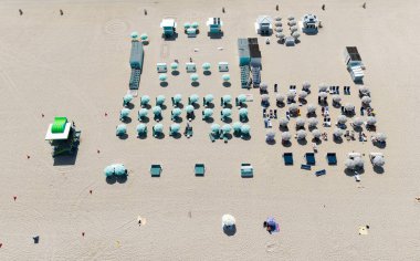 Güneş yatağı ve şemsiyeli kumsal manzarası. Yaz tatili. Yazın deniz kenarında tatil. Deniz, plaj şemsiyesi altında rahatlar. Denize açılın. Lüks tatil köyü. Plaj tatili.