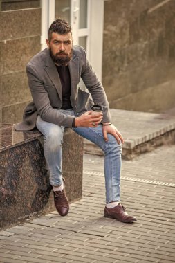 Kahve molası. Günlük stil rutini. Sakallı adam şehir caddesinde kahve içiyor. Sokakta elinde kahve tutan yakışıklı bir adam. İş hayatı, mola. Sabah kahvesi içen adam. Erkek modeli.