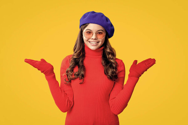 Trendy portrait of fall style. Girl in autumn jumper isolated on yellow. Teen girl wear sunglasses. Autumn fashion girl. Trendy and stylish teenager girl presenting product. Fall style for teen.
