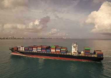 Yük konteynırı kargo gemisine yüklendi. Hava görüntülü kargo gemisi limana giriyor. Kargo işi. Konteyner gemisi. Nakliye lojistiği. Liman operasyonları. Kargo gemisi denizde, hava manzaralı..