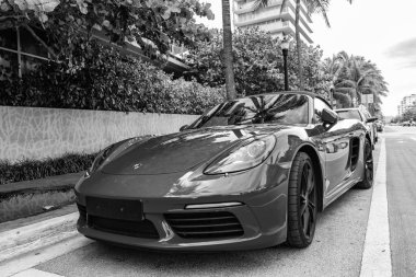 Miami Beach, Florida USA - 9 Haziran 2024: 2018 Porsche 718 Boxter 's orange color at Miami Beach. Ocean 'daki lüks araba porshche' si Miami plajına gidiyor. ön görünüm