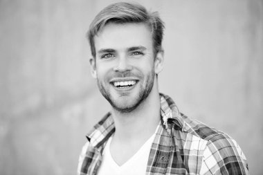 Milenyum erkeğinin gündelik tarzı. Sıradan tişörtlü bir adamın portresi. Tıraşsız adamın şık bir portresi. Dışarıdaki yakışıklı genç adam. Milenyum adamı gülümsüyor ve kareli gömlek giyiyor..