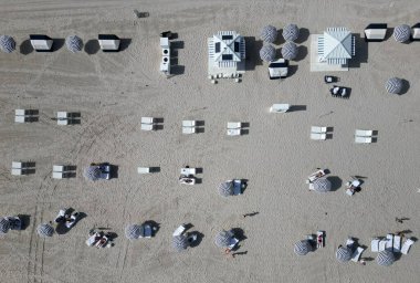 Yazın deniz kenarında tatil. Deniz, plaj şemsiyesi altında rahatlar. Denize açılın. Lüks tatil köyü. Güneş yatağı ve şemsiyeli kumsal manzarası. Yaz tatili. Deniz tatili.