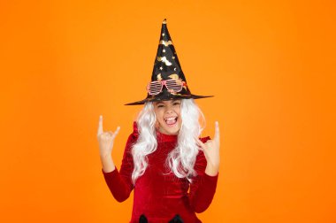 Cadı kostümlü genç kız. Mutlu Cadılar Bayramı. Cadılar Bayramı kostümlü cadı kız turuncu üzerine izole edilmiş. Şeker mi şaka mı? Cadılar Bayramı 'nın tüm bayramlarını kutlayın. Tüm Cadılar Bayramı. 31 Ekim. Eğleniyorum..