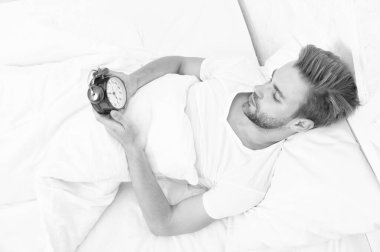 Uykucu adam yatakta yatarken elindeki çalar saate bakıyor. Sabah uyanışı. Uykulu adam çalar saati kapatıyor. Erken kalkmak. Uyanma ve kalkma vakti geldi. Sabah uyanması. Hastalık izni.