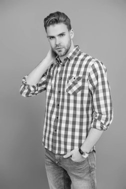 Kareli gömlek giyen milenyum adamı. Milenyum erkeğinin gündelik tarzı. Sıradan tişörtlü bir adamın portresi. Tıraşsız adamın zarif portresi. Gri yolda izole edilmiş bir adam. Günlük düğmeli gömlek..