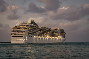 Gece vakti ışıltılı lüks yolcu gemisi yolculuğunun havadan görünüşü. Gemi Miami sahil limanından ayrılıyor. Gemi seyahati. Yaz tatilindeki deniz yolculuğunun havadan görünüşü. Gemi turu ve deniz yolculuğu..