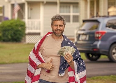 Amerikan vergi politikası. İspanyol adam ve Amerikan bayrağı. Amerika 'da vergi ödemek. Katma değer vergisi. Vergi sistemi. Vatansever adam. Amerikan bayrağı ve dolar parası olan adam. Enflasyon konsepti. Başparmak yukarı..