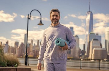 Vücuduna uygun. Yoga koçu. Sporcu adam antrenmana hazır. Sağlıklı bir yaşam tarzı. Spor ve spor. Eğitim için yoga minderi. New York 'ta sporcu. Manhattan 'da spor kıyafetli bir adam. NY yoga.