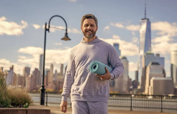 Vücuduna uygun. Yoga koçu. Sporcu adam antrenmana hazır. Sağlıklı bir yaşam tarzı. Spor ve spor. Eğitim için yoga minderi. New York 'ta sporcu. Manhattan 'da spor kıyafetli bir adam. NY yoga.
