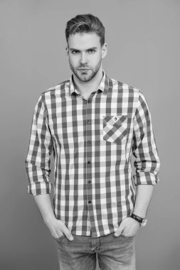 Tıraşsız adamın zarif portresi. Gri yolda izole edilmiş bir adam. Kareli gömlek giyen milenyum adamı. Milenyum erkeğinin gündelik tarzı. Sıradan tişörtlü bir adamın portresi. Erkek giyim.