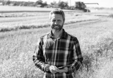 Tarlada tableti olan çiftçi tarımcı adam. Modern tarımın teknolojisi. Tarlada tabletle çalışan çiftçi. Tablet çekli İspanyol çiftçi. Ekin hasadı.