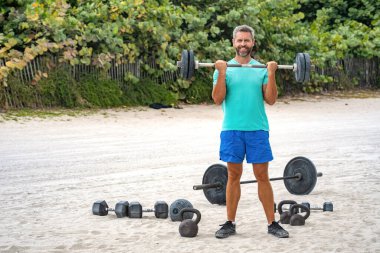 Güçlü, mutlu adam spor egzersizi yapar. Jimnastik. Halterli sporcu. Sağlıklı yaşam halter eğitimi. Olgun bir adam dışarıda halter egzersizi yapıyor. Halter kaldıran sporcu, boşluğu kopyala.
