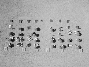 Deniz, plaj şemsiyesi altında rahatlar. Denize açılın. Güneş yatağı ve şemsiyeli, kumlu, egzotik kumsal manzarası. Sahilde güneşlenen insanlar. Yaz tatili. Yazın deniz kenarında tatil..