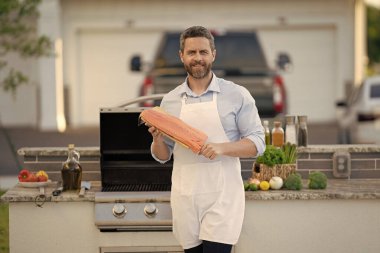 İspanyol adam ızgarada ton balığı hazırlıyor. Şef, deniz ürünlerini ızgara yapıyor. Arka bahçede barbekü. İnsan balığı pişirir. Önlüklü, kızarmış balıklı bir adam. Izgara ve barbekü. Barbekü ve ızgara. Açık havada ızgara..