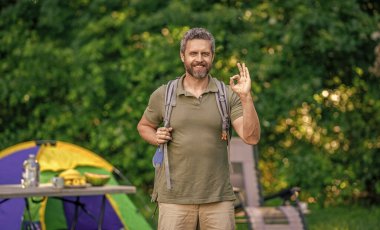 Yaz günü doğa yürüyüşçüsü. Yaz kampı ve doğa tatili. Yaz kampındaki adam. Kamp macerası. Yürüyüş konsepti. Kamp çadırı. Ormanda çadırlı sırt çantalı bir adam..