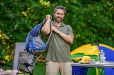 Kamp alanındaki adam. Piknik zamanı. Ormanda çadırlı piknik yapan bir adam. Yaz günü yürüyüş yapan bir adam. Yaz kampı aktivitesi. Yaz kampı. Kamp macerası. Yürüyüş yaşam tarzı. Yürüyüş rotası.