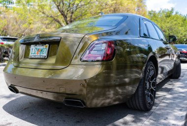 Miami, Florida, ABD - 18 Nisan 2025: Araç 2024 Rolls Royce Ghost açık havada park etti. Altın araba, köşe manzaralı. 2024 Rolls Royce Hayalet sedan arabası. Lüks sedan araba Rolls Royce Hayalet.