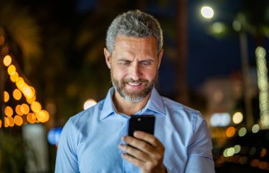 İş adamı cep telefonuyla konuşuyor. İş sohbeti. İş adamı gülümsüyor ve telefonda konuşuyor. Akıllı telefon kullanan bir iş adamı. Başarılı bir iş adamı internette sohbet ediyor. Dışarıdaki iş adamı..