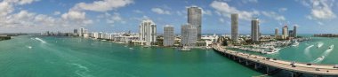 Miami silueti ve Biscayne Körfezi Panoraması. Kıyı gökdelenleri olan panoramik şehir manzarası. Miami Beach 'in yukarıdan manzarası. Drone Fisher Adası 'nı ve limanı ele geçirdi.