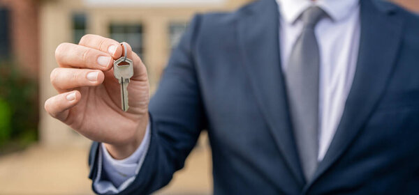 Риэлторы держат ключи под открытым небом. Агент по недвижимости выставляет дом на продажу. Страхование имущества. Рынок недвижимости. Брокер с ключом от дома. Страховка. Риэлтор предлагает новый дом, копирующее пространство.