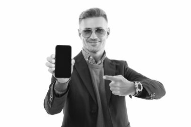 İş uygulamasının reklamı. Olgun iş adamı telefon ekranını sunuyor. İş adamı, telefonun beyazda izole olduğunu gösteriyor. Adam yeni iş telefonu uygulamasını gösteriyor. Ürünü sunuyorum. İşaret parmağı.