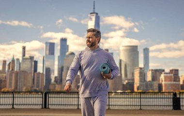 Manhattan 'da spor kıyafetli bir adam. Vücuduna uygun. Yoga koçu. Sporcu adam antrenmana hazır. Sağlıklı bir yaşam tarzı. Spor ve spor. Eğitim için yoga minderi. New York 'ta sporcu.