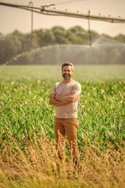 Çiftçi adam. Su püskürtme sulama tarlası. Damlatma sulama sistemi. Ekin sulama. Tarım ve tarım. Sulama sisteminde tarımı sulayan bir adam. Fıskiye sulama.
