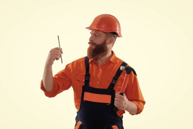 Üniformalı tamircinin çekici var. Çekiçle sakallı tamirci. Marangoz, beyaz çiviyle tamir ediyor. Tamirci. Adam çekiç çivisi tutuyor. Marangozluk ve onarım.