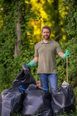 Çöp yığını. Gezegen kirliliği çevresel koruma. Ormanı temizliyorum. Çöp torbasına çöp koymak, çevre koruması. Gönüllü, çöpleri toplamaya yardım eder. Açık hava temizliği.