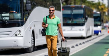 Miami 'de olgun bir turist. Bavullu sıradan giysili bir gezgin. İnsan hafta sonu yurt dışına çıkıyor. Seyahat yaşam tarzı. Yaz şehrinde bir turist. Seyahat çantası. Amerika 'ya yaz gezisi. Otobüs durağı.