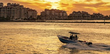 Yat, Sunset Marina 'ya git. Tekne ve yat gezisi. Lüks bir yaşam tarzı. Fisher Adası 'nda lüks bir binada yat. Yaz tatili. Fisher Adası gün batımı. Lüks motorlu tekne yatı. Boşluğu kopyala.