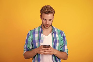 Telefon görüşmesi. Mobil iletişim. İletişim. Akıllı telefondan mesaj atan adam sarıda izole edilmiş. Millennial 'daki adam mesajlaşmak için telefonu kullanıyor. İnternette sohbet ediyoruz. Akıllı telefondan mesaj atan adam.