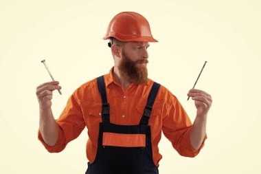 Marangoz, beyaz çiviyle tamir ediyor. Tamirci. Adam çekiç çivisi tutuyor. Marangozluk tamir ve çekiç. Üniformalı tamircinin çivisi var. Sakallı marangoz çivi tutar. Marangozluk işi.