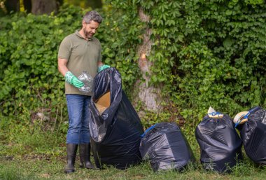 Kirli orman. Çöp yığını. Gezegen kirliliği çevresel koruma. Ormanı temizliyorum. Çöp torbasına çöp koymak, çevre koruması. Gönüllü çöp toplamaya yardım eder, alanı kopyalar.