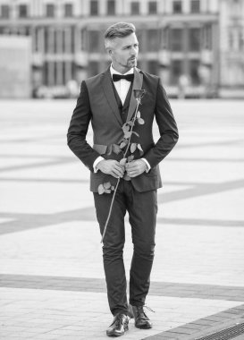 Siyah smokinli zarif bir adam. Smokin papyon takan adam dışarıda. Dışarıda kırmızı güllü smokin giyen adam..