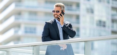 Akıllı telefonlu İspanyol bir iş adamı. İş iletişimi. Telefona cevap veren adam. Zengin iş adamı dışarıda telefonla konuşuyor. Telefon kullanan bir iş adamı. Erkek telefon konuşması. Şirket konuşması.