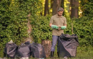 Gönüllü adam ormanda çöp topluyor. Çevresel koruma. Çevreci adam. Çevresel koruma. Çevreyi koru. Çevre plastik kirliliği. Atık toplama servisi.