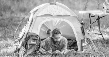 Yürüyüş yaşam tarzı. Sakin ol ve kamp alanında kitap oku. İlham zamanı. Çadırda piknik yapan bir adam. Yaz günü yürüyüş yapan bir adam. Yaz kampı ilhamı. Yaz kampı. Kamp macerası.